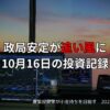 夕焼けを背景にしたトレーディングルーム。複数のモニターに株価チャートや金融データが表示され、「政局安定が追い風に｜10月16日の投資記録」という日本語テキストが重ねられている。