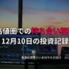 複数のモニターに株価チャートと金融データが表示されたトレーディング環境。窓の外には夕焼けが広がり、12月10日の投資活動を記録する場面。